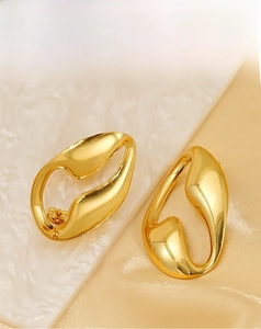 Detailed close-up of golden hollow irregular oval earrings with a polished mirror finish