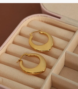Detailed close-up of golden U-shaped hollow teardrop earrings in a pink velvet jewelry box