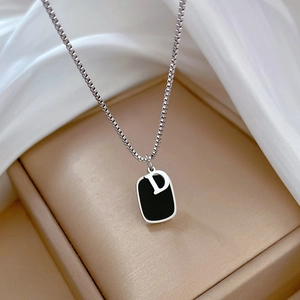 Detailed macro view of titanium steel square pendant with letter D on gold necklace
