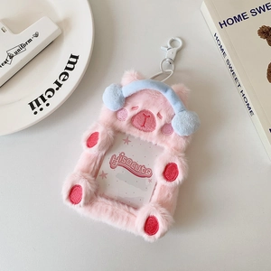 Macro detail of pink plush bear photocard holder with blue earmuffs and white hook