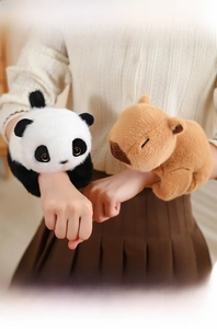 Close-up of cute plush panda and capybara snap bracelets worn on a wrist for kids