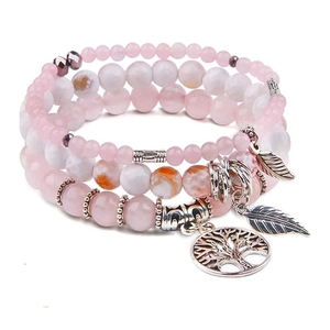 Close-up of tree of life and leaf charms on pink beaded bohemian layered bracelets