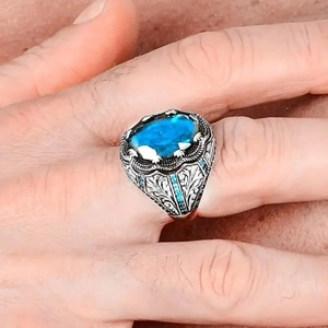 Dettaglio anello vintage argento con incisioni decorate e grande gemma blu ovale