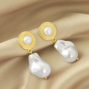 Detail of vintage baroque pearl earrings with golden textured base on champagne silk