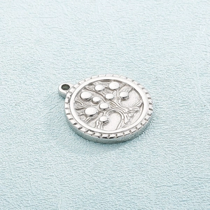 Close-up of silver stainless steel circular tree of life pendant with embossed details