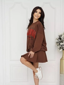 Dettaglio della felpa marrone oversize con stampa California e minigonna a pieghe