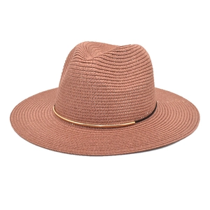 Detail of red woven straw fedora hat featuring a black band and gold metal accessory