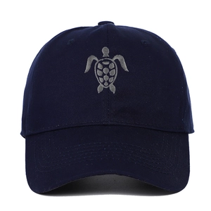Close-up of a navy cotton baseball cap featuring detailed grey sea turtle embroidery