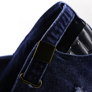 Detail of dark denim baseball cap with an adjustable bronze metal buckle and stitching