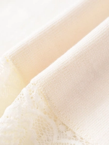 Dettaglio macro della maglia a coste e del pizzo bianco su una gonna midi beige