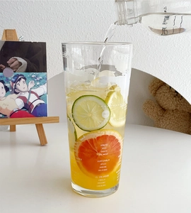 Detail view of 1L large glass tumbler with citrus fruit drink and ice in a bright setting