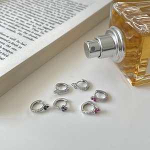 Detail of 925 silver hoop earrings with mini zircons and clover shaped gemstones