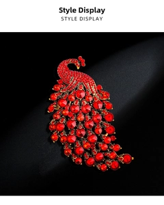 Macro view of crystal peacock brooch showing red rhinestones and gold-plated metal texture