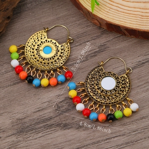Detail view of bohemian bell tassel earrings with dimensions 5.3cm by 4.8cm on wood