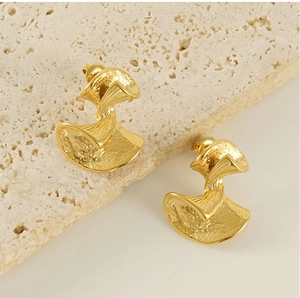 Macro view of golden fan-shaped earrings with abstract hammered texture on stone