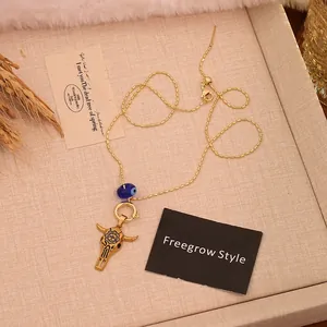 Detail of vintage gold bull head pendant necklace with blue evil eye bead on textured fabric