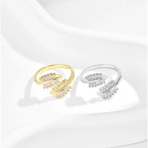 Close-up of gold and silver leaf rings with marquise zircon stones on white silk fabric