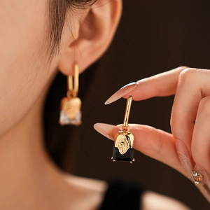 Detailed close-up of golden lion head earrings featuring elegant square black stones