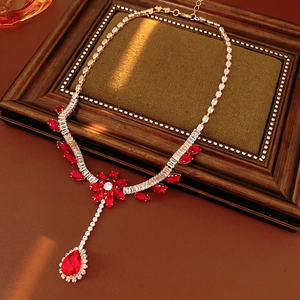 Detail of red flower teardrop pendant necklace on brown leather within a frame