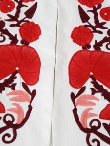 Detailed macro view of high-quality red and pink floral embroidery on white blazer fabric