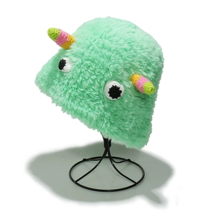 Chapeau bob monstre en peluche verte avec yeux tricotés et cornes colorées sur support