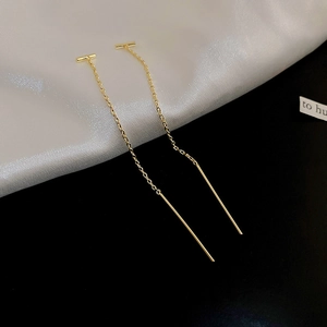 Vue détaillée des boucles d'oreilles pendantes dorées à pampilles sur soie et fond noir