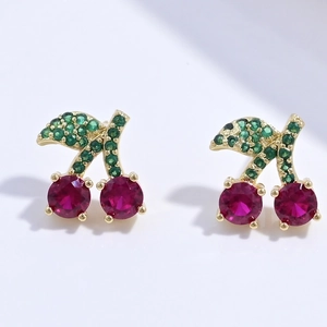 Creative gold cherry stud earrings with red and green cubic zirconia stones on white back