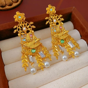 Primer plano de pendientes vintage dorados con pájaros, flores y perlas