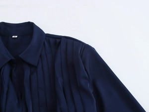 Detail shot of the size S label and elegant pleated texture on a navy satin dress