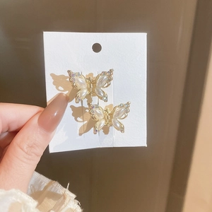Macro shot of two gold butterfly hair clips with pearls and rhinestones on card