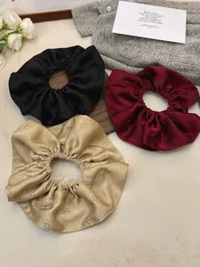 Detailed view of three-piece set of jacquard satin scrunchies with rose embossing
