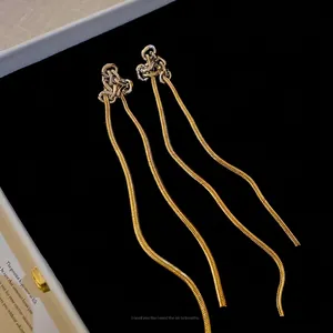 Boucles d'oreilles nœud argent avec de longues chaînes serpent dorées sur velours