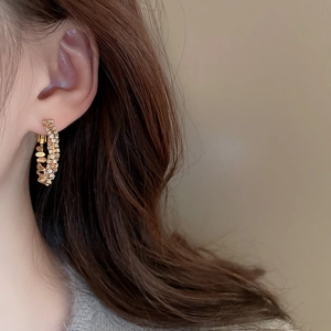 Close-up of model wearing gold double-layer C-shaped hoop earrings with zircons