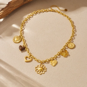 Gold vintage necklace with heart, sunflower, and clover pendants on a chunky chain