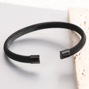 Detail shot of black woven mesh texture on stainless steel C-shaped cuff bracelet