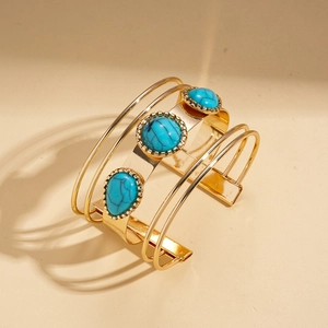 Detail of bohemian gold open bangle with triple turquoise stones and layered cutouts