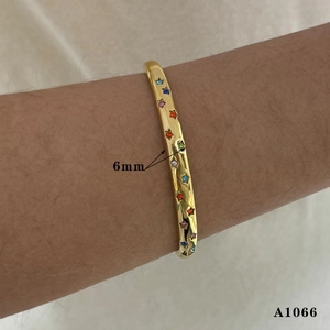 Detail view of a 6mm wide gold plated cuff bracelet with colorful star shaped stones