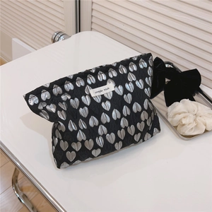 Detail of jacquard silver heart pattern on black canvas cosmetic bag with simple wish label