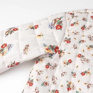 Close-up of diamond-quilted floral jacket featuring colorful patterns on white base