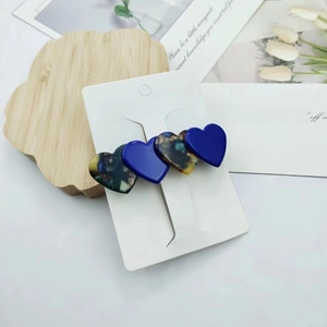 Detailed view of acetate heart hair clip in blue and tortoiseshell with gold lettering