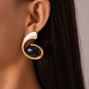 Detailed side view of a large golden C-shaped earring with a black oval gemstone