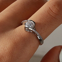 Close-up of a silver heart ring with twisted band and sparkling round diamond setting