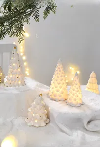Detail of white ceramic Christmas tree with golden dots and warm LED glow for table decor