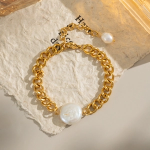 Detail of chunky gold chain bracelet featuring a large baroque pearl and lobster clasp