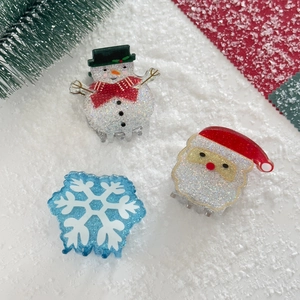 Detailed view of acrylic Christmas hair clips featuring snowman and Santa glitter designs