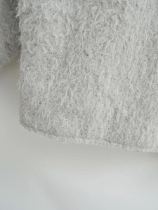 Detailaufnahme der flauschigen grauen Webpelz-Textur des Wollmantels mit feinen Faserdetails