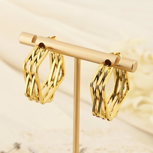 Modern layered geometric gold earrings on a display stand with irregular metal frames