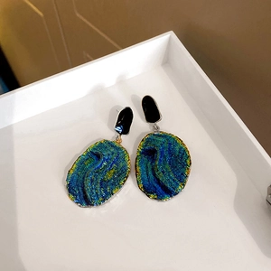 Detail of vintage resin earrings with black enamel studs and teal faux stone pendants