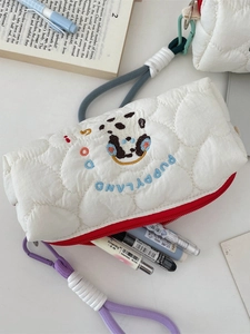 Quilted white pencil case with puppy embroidery and red zipper on a desk setup