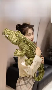 Detail of soft green crocodile plush toy with mesh texture held by a model